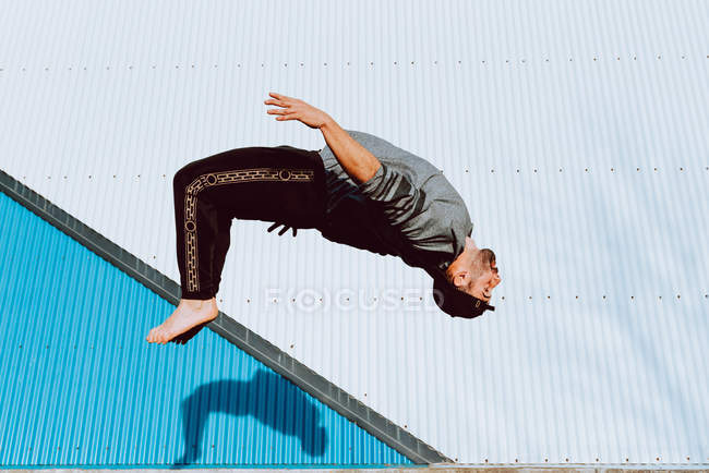 Barfuß-Typ in stylischem Outfit, der in der Nähe der Mauer eines modernen Gebäudes Flip-Flop macht — Stockfoto