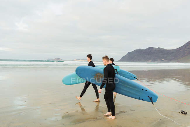 Pessoas com prancha de surf andando perto do mar — Fotografia de Stock