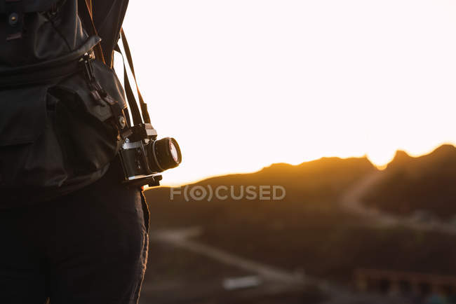 Крупный план туриста с рюкзаком и ретро-камерой, стоящей на горе Тейде вечером на размытом фоне на Тенерифе, Канарские острова, Испания — стоковое фото