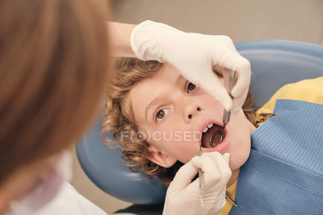 Руки врача, делающего сканирование зубов маленького мальчика во время работы в стоматологической клинике — стоковое фото