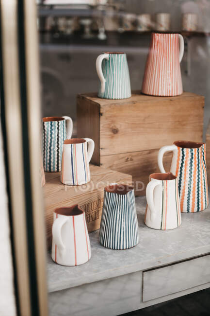Set of cute ceramic jugs with various ornaments placed behind shop window on street of Lisbon, Portugal — Stock Photo