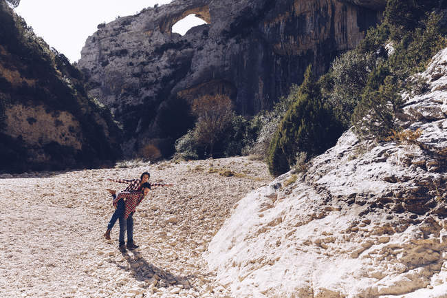 Молода пара грає в каньйоні між скелястими горами в сонячний день — стокове фото