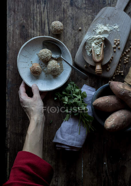 Person rolling in breadcrumbs sweet potatoes — Stock Photo
