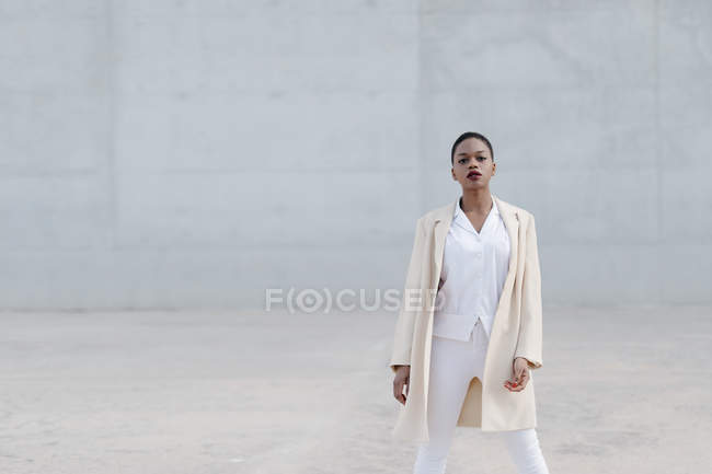 Мода короткошерста модель в білому вбранні позує на сіру стіну — стокове фото