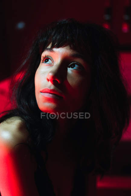 Sensual young brunette woman looking away between redness — Stock Photo