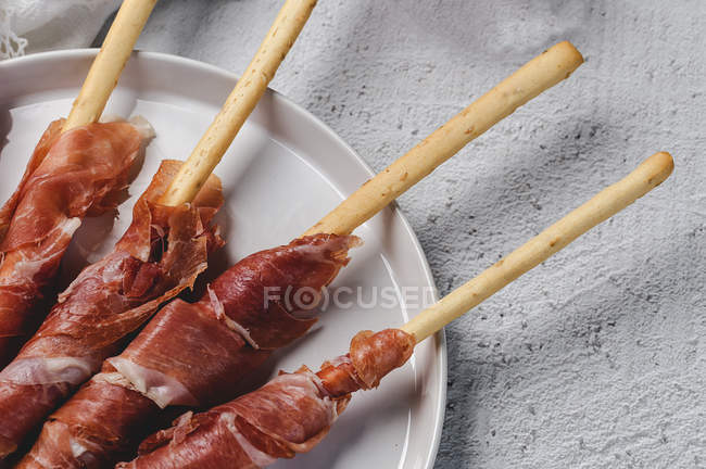 Gressinis com presunto serrano típico espanhol na placa branca — Fotografia de Stock