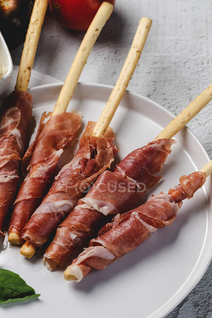Gressinis with spanish typical serrano ham on white plate — Stock Photo