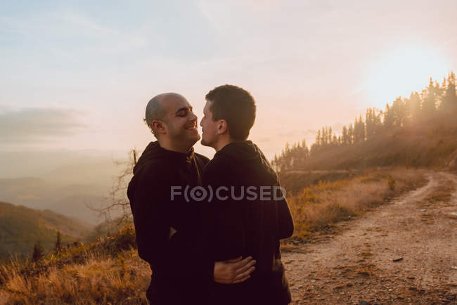 Felice coppia omosessuale abbracciare e baciare sul sentiero nella foresta nella giornata di sole — Foto stock