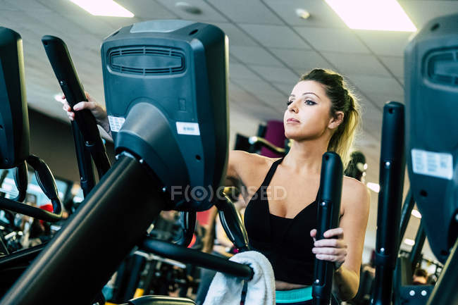 Mujer bonita en la máquina de ejercicio en el gimnasio - foto de stock