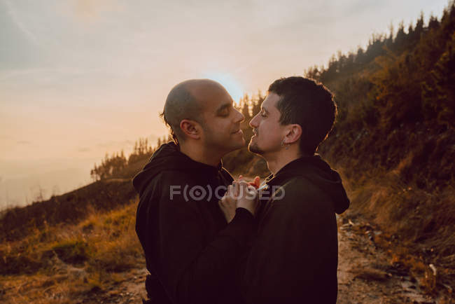 Щаслива гомосексуальна пара обіймає і цілує на шляху в лісі в сонячний день — стокове фото