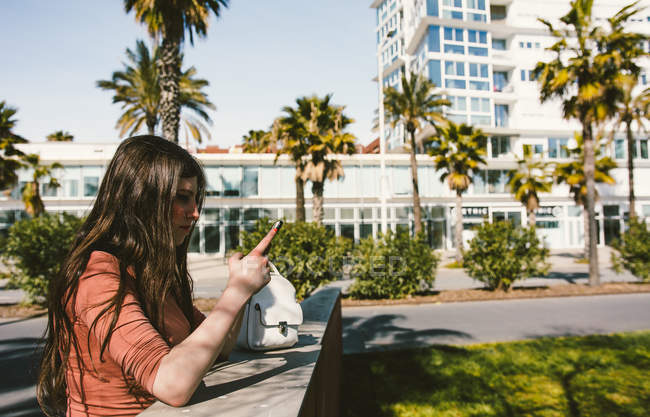 Teen ragazza guardando il suo smartphone per strada in una giornata di sole — Foto stock
