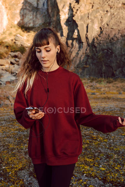 Молодая вдумчивая хипстерша слушает музыку с мобильного телефона и ходит по природе — стоковое фото