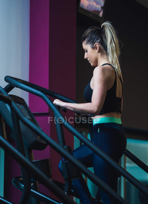 Mujer bonita en la máquina de ejercicio en el gimnasio - foto de stock