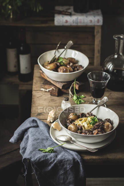 Prato tradicional Boeuf Bourgingnon servido com macarrão lado em tigelas em mesa de madeira — Fotografia de Stock