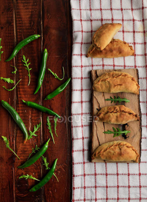 Tortini fatti in casa e peperoncini verdi freschi con foglie di rucola sul tavolo di legno — Foto stock
