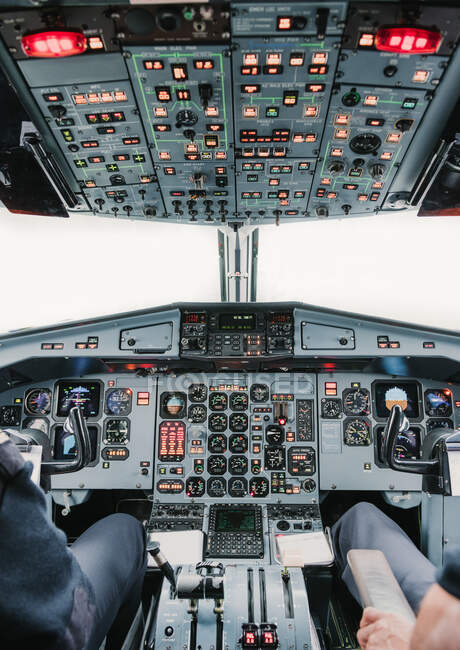 Два анонімних чоловіка сидять біля панелі приладів всередині кабіни сучасних літаків під час польоту — стокове фото