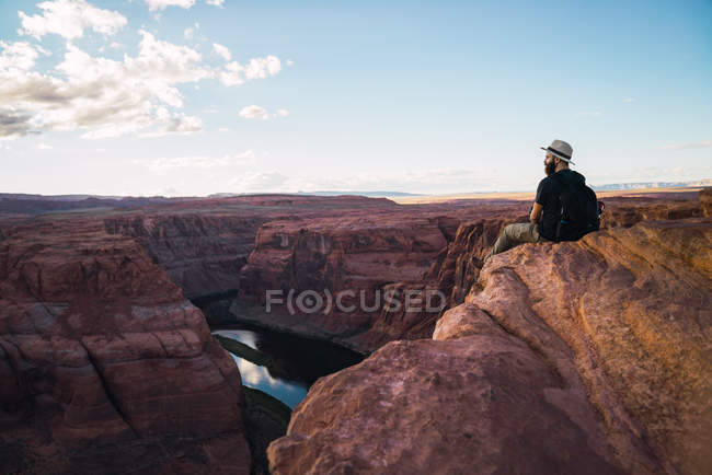 Vista posteriore del ragazzo barbuto con lo zaino guardando il bellissimo canyon e il fiume calmo nella giornata di sole sulla costa occidentale degli Stati Uniti — Foto stock