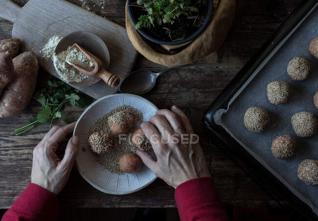 Person rolling in breadcrumbs sweet potatoes — Stock Photo