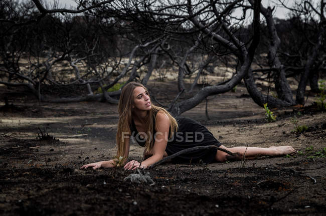 Giovane ballerina in nero in posa su terra tra boschi secchi — Foto stock