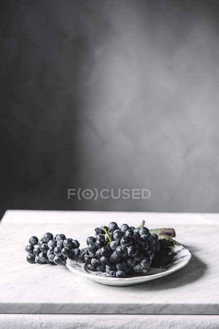 Bunch of fresh grapes on plate on table — Stock Photo