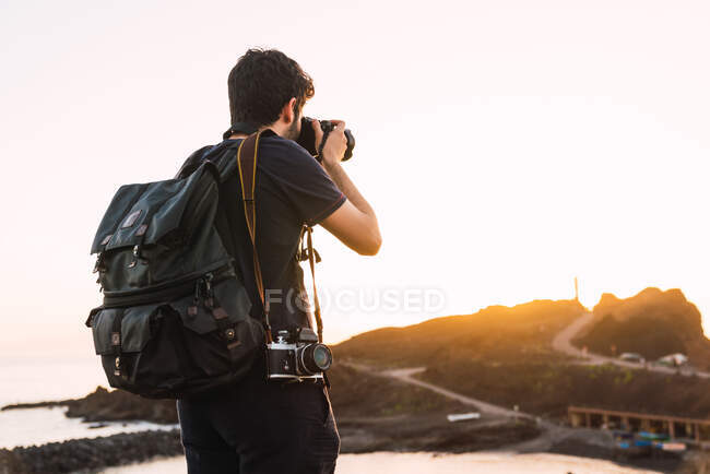 Vue arrière du touriste avec sac à dos et caméra rétro debout sur la montagne Teide en soirée sur fond flou à Tenerife, Îles Canaries, Espagne — Photo de stock