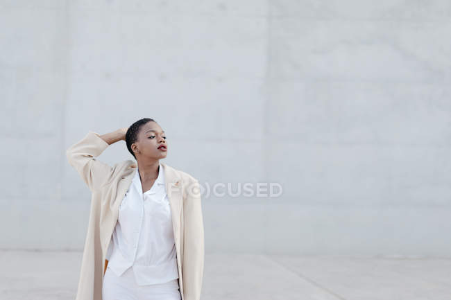Mode kurzhaariges Model in weißem Outfit posiert gegen graue Wand — Stockfoto