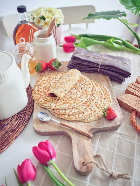 Breakfast with pancakes and strawberries on kitchen table with flowers — Stock Photo