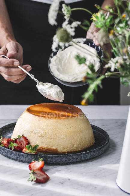 Crop hand putting whipped cream on caramel flan custard — Stock Photo