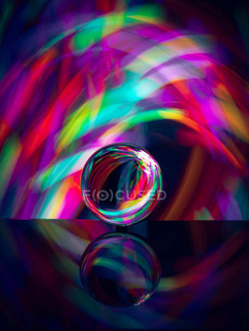 Crystal ball on surface with reflection near abstract shines — Stock Photo