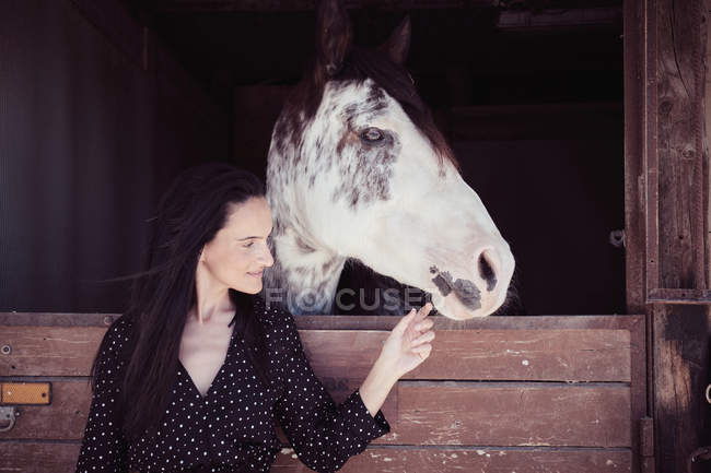 Приваблива чарівна жінка з закритими очима зворушлива кінь в стійло — стокове фото
