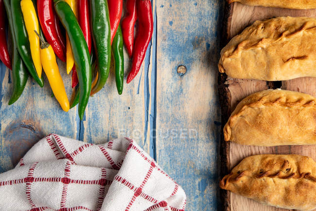 Набір домашніх пирогів і свіжий зелений і червоний перець чилі на сірому дерев'яному столі — стокове фото