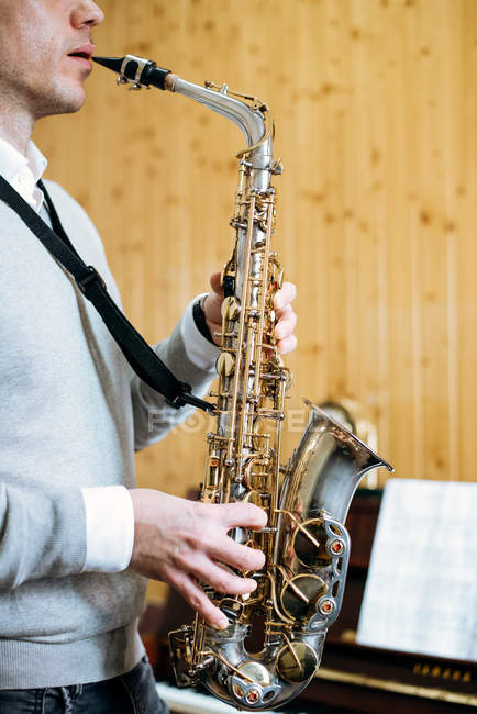 Cropped unrecognizable man playing saxophone in studio — Stock Photo
