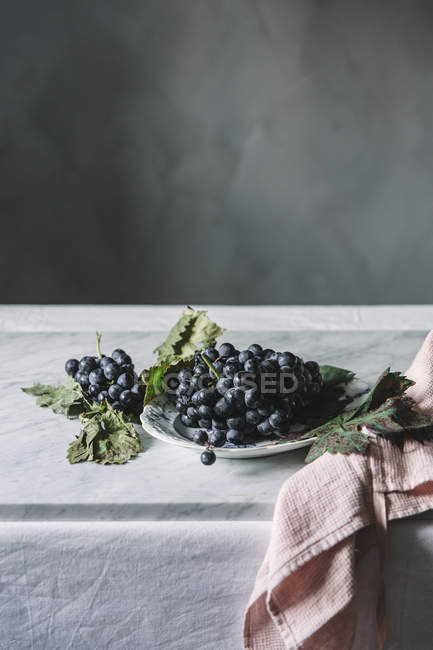 Група свіжого винограду на тарілці на столі — стокове фото
