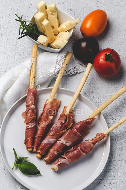 Грессинс з іспанською мовою, типовий Барано, на білій тарілці зі свіжими помідорами та сиром — стокове фото
