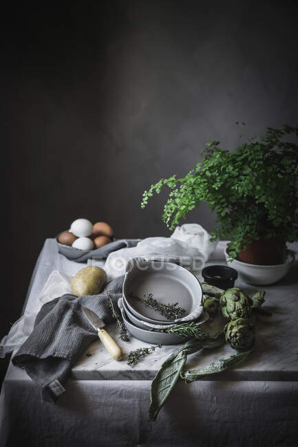 Uova e diverse erbe in ciotole poste su tavola rustica — Foto stock