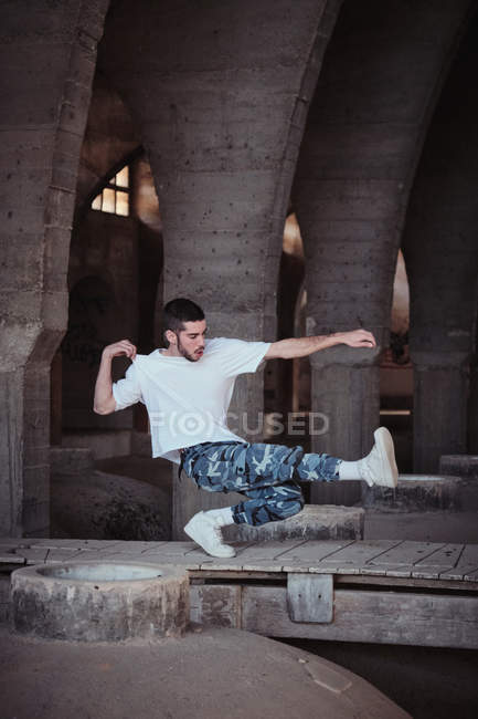 Junger Kerl in stylischem Outfit tanzt modernen Tanz im alten schäbigen Gebäude — Stockfoto