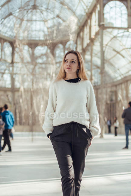 Stilvoll lächelnde junge Frau zu Fuß in Kristallpalast in Madrid, Spanien — Stockfoto