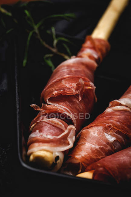 Close-up of gressinis with spanish typical serrano ham on dark background — Stock Photo