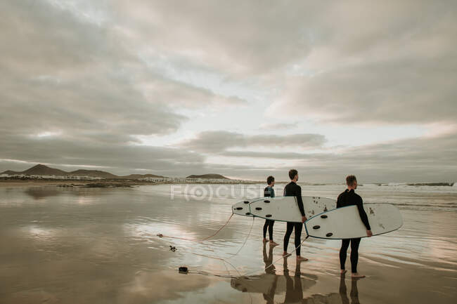 Люди з дошкою для серфінгу, що йдуть біля моря — стокове фото