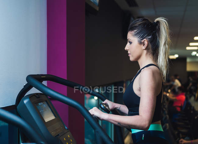 Pretty woman on exercise machine in gym — Stock Photo