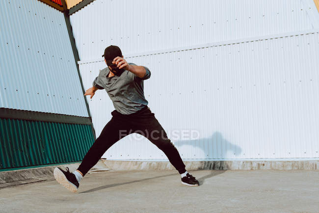 Хлопець розбиває танці біля стіни сучасної будівлі на міській вулиці — стокове фото