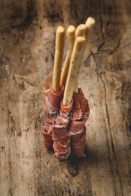 Gressinis com presunto serrano típico espanhol na mesa de madeira rústica — Fotografia de Stock