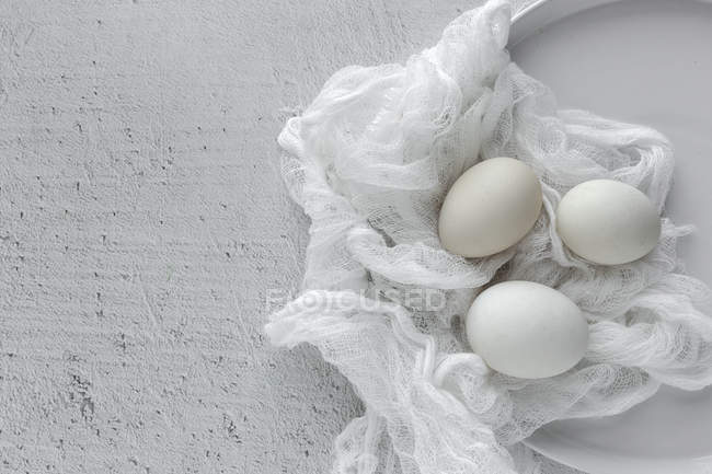 Huevos blancos sobre tela sobre mesa de madera - foto de stock