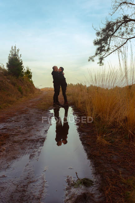 Water slop with reflection of homosexual couple embracing and kissing on road — Stock Photo
