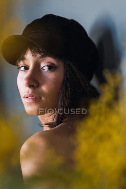 Young charming brunette woman in cap looking at camera — Stock Photo