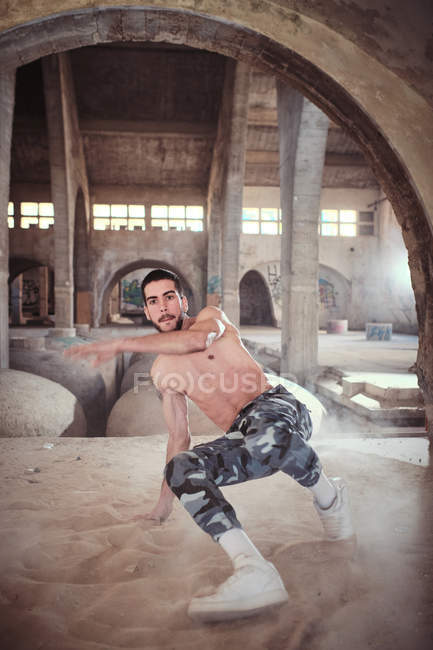 Чоловік танцює в старій будівлі на піску — стокове фото
