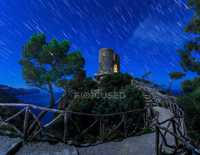 Luci dalla torre sulla cima di alta collina vicino al mare e cielo meraviglioso in serata — Foto stock