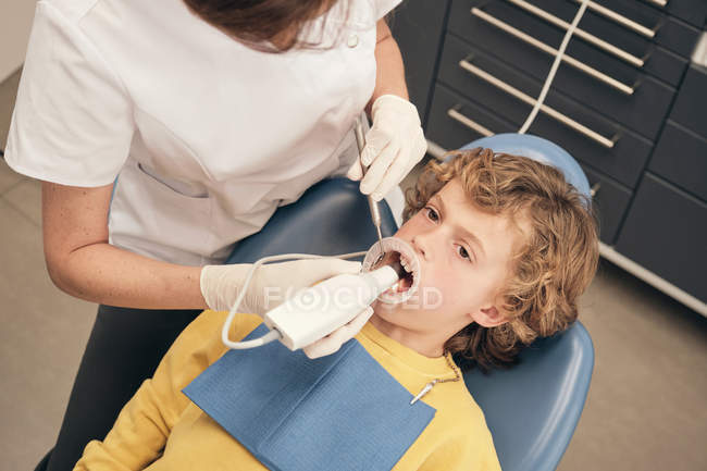 Mãos de médico fazendo a varredura dos dentes do menino enquanto trabalhava na clínica odontológica — Fotografia de Stock