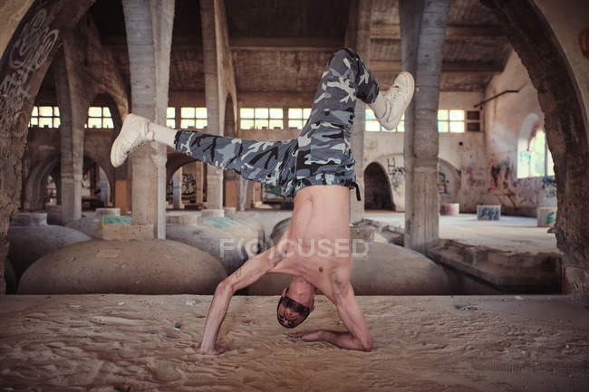 Hemdloser Mann tanzt auf Sand in verwittertem Gebäude — Stockfoto