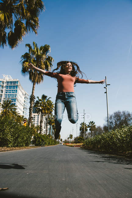 Дівчина-підліток щасливо йде вулицями міста в сонячний день — стокове фото
